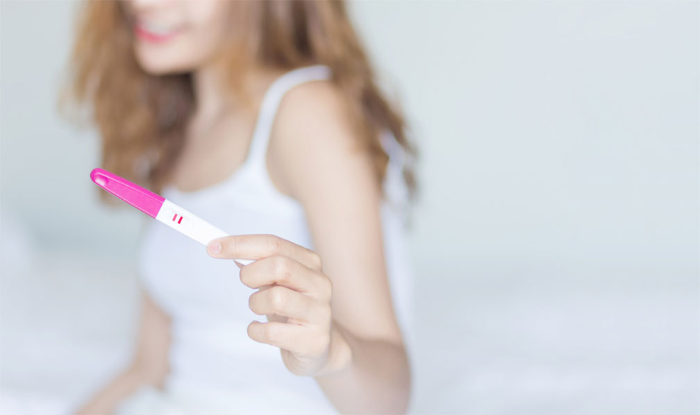Reiki for fertility, woman holding positive pregnancy test