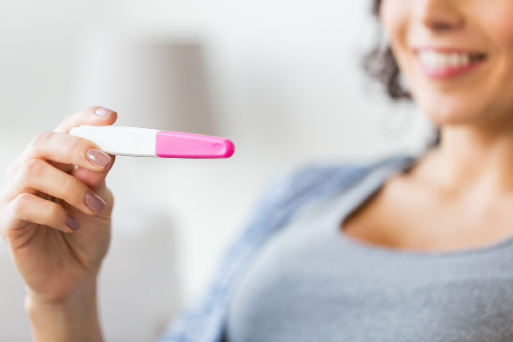 woman looking at positive pregnancy test